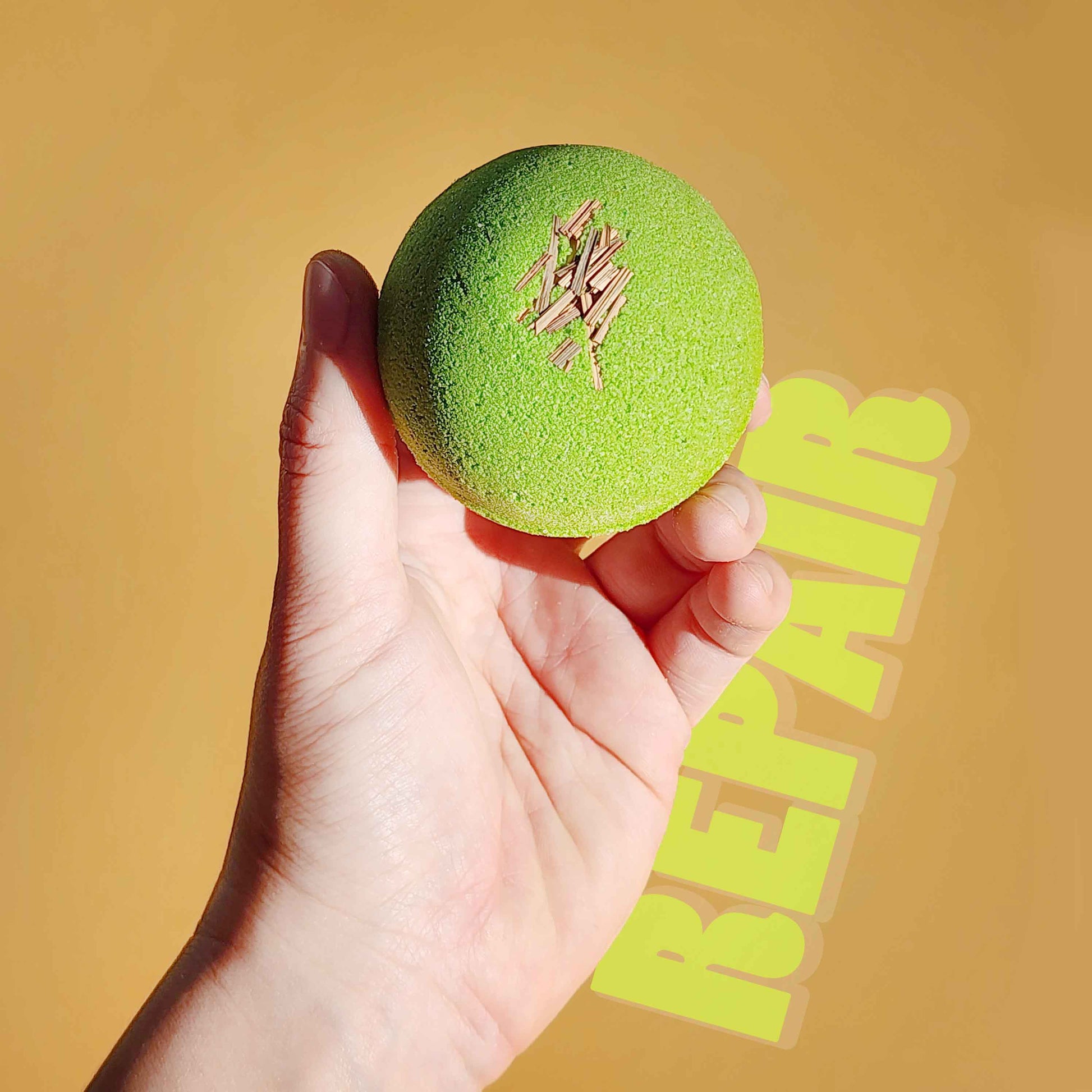 Hand holding the green Repair aromatherapy bath bomb