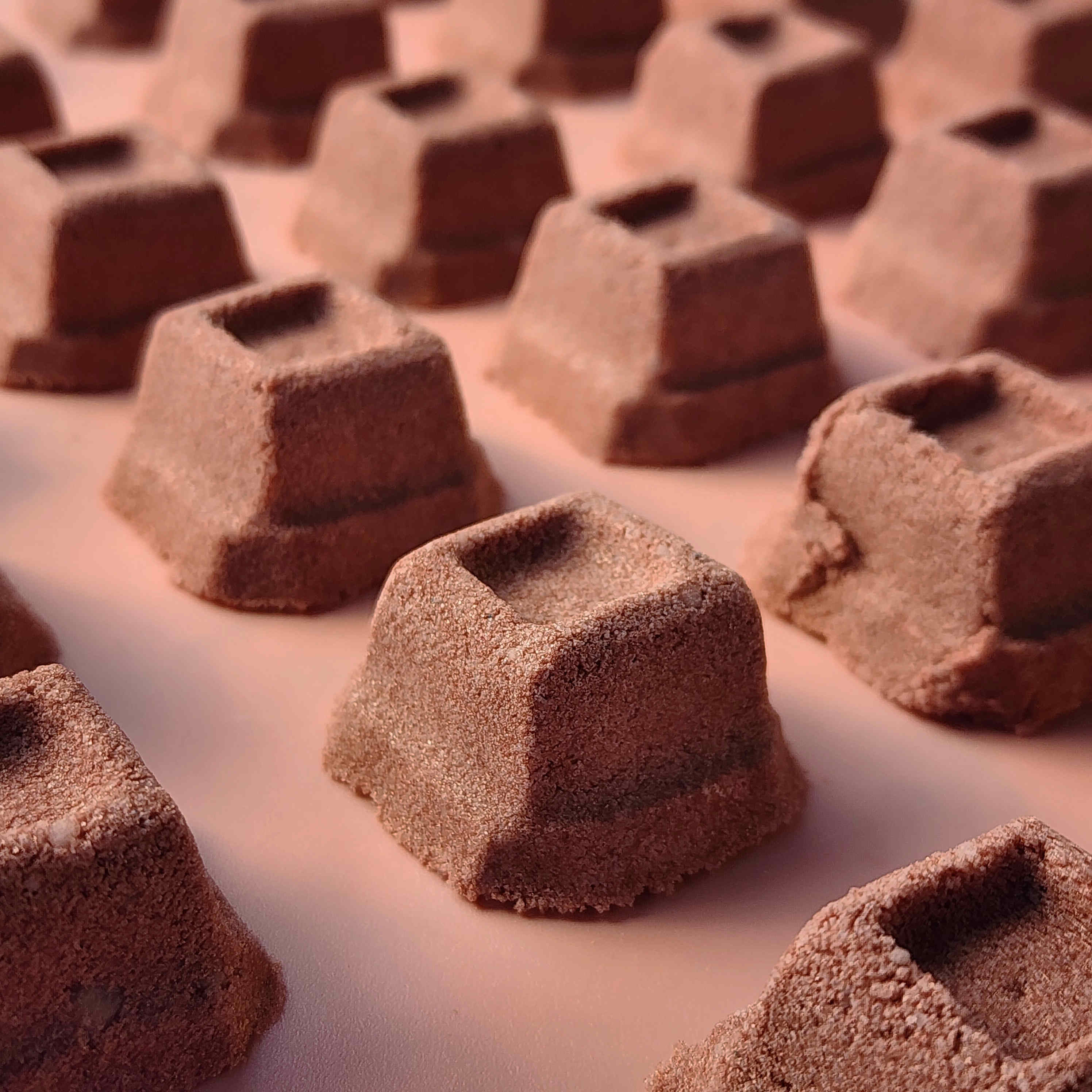 mini chocolate bath bombs shaped like cubes of chocolate on a plain brown background