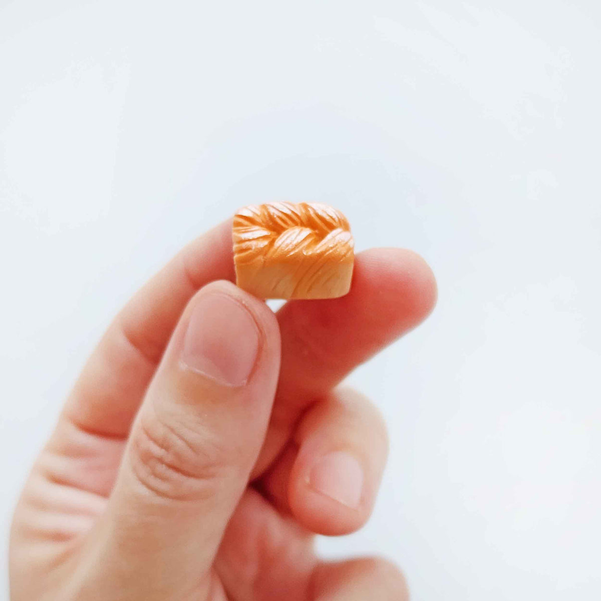 Hand holding a miniature bread-loaf surprise toy