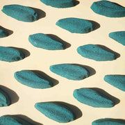 deep green long leaf shaped bath bombs laid out neatly on a plain beige background