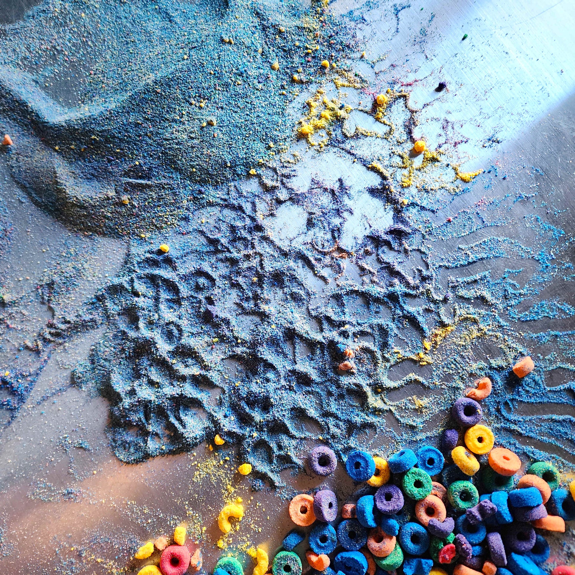 bath bomb dust scattered across a table surface with small fruit loop shaped bath bombs