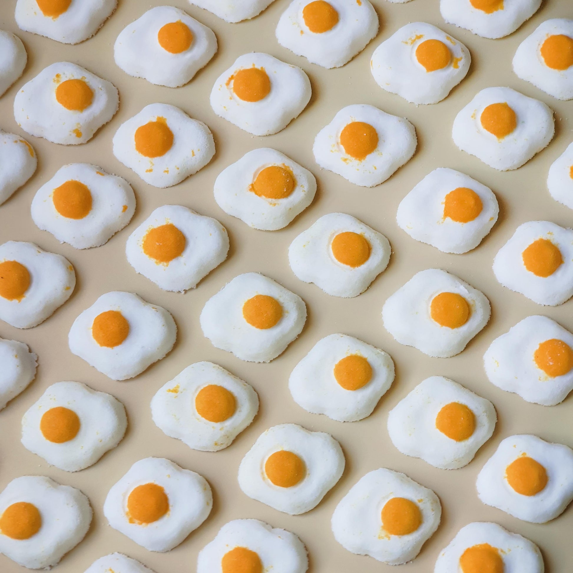 Mini sunny side up egg shaped bath bomb with a golden orange yolk