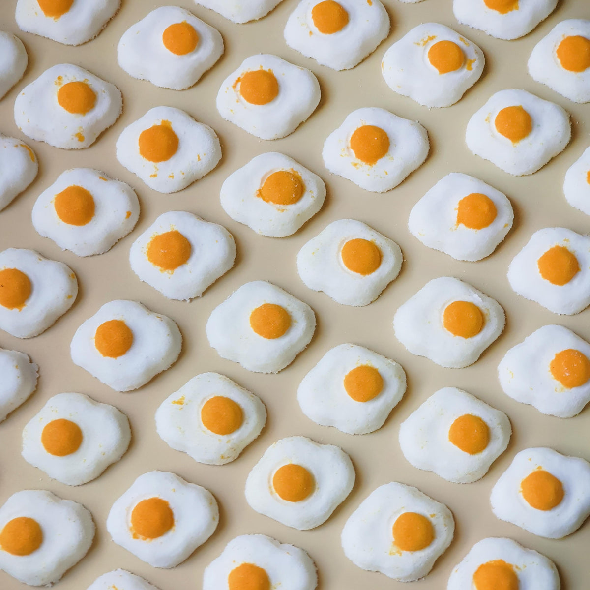 Mini sunny side up egg shaped bath bomb with a golden orange yolk