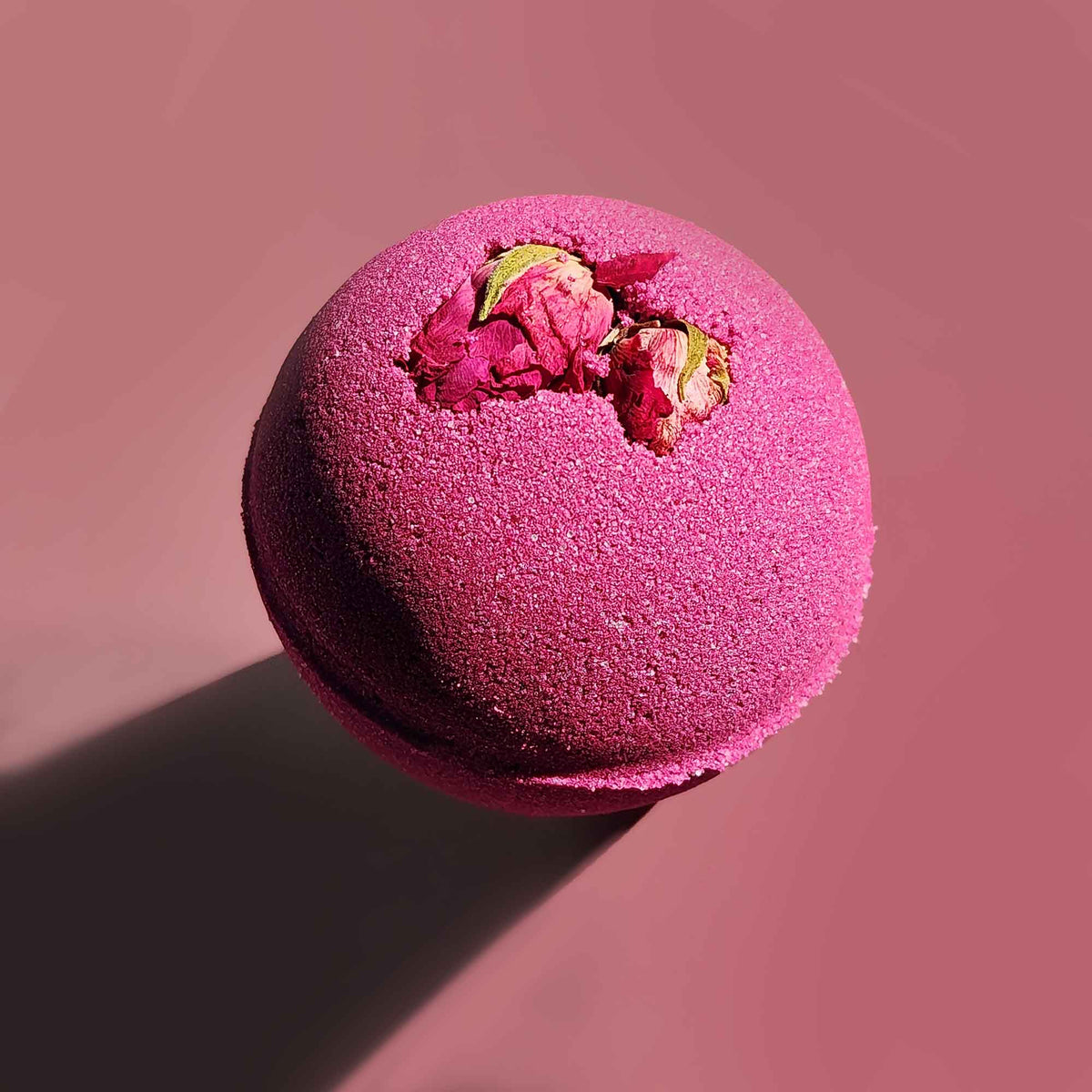 velvet red round aromatherapy bath bombs with dried rose buds on a dusty pink background