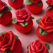 Red circular bath bomb with a rose on top on a pink background