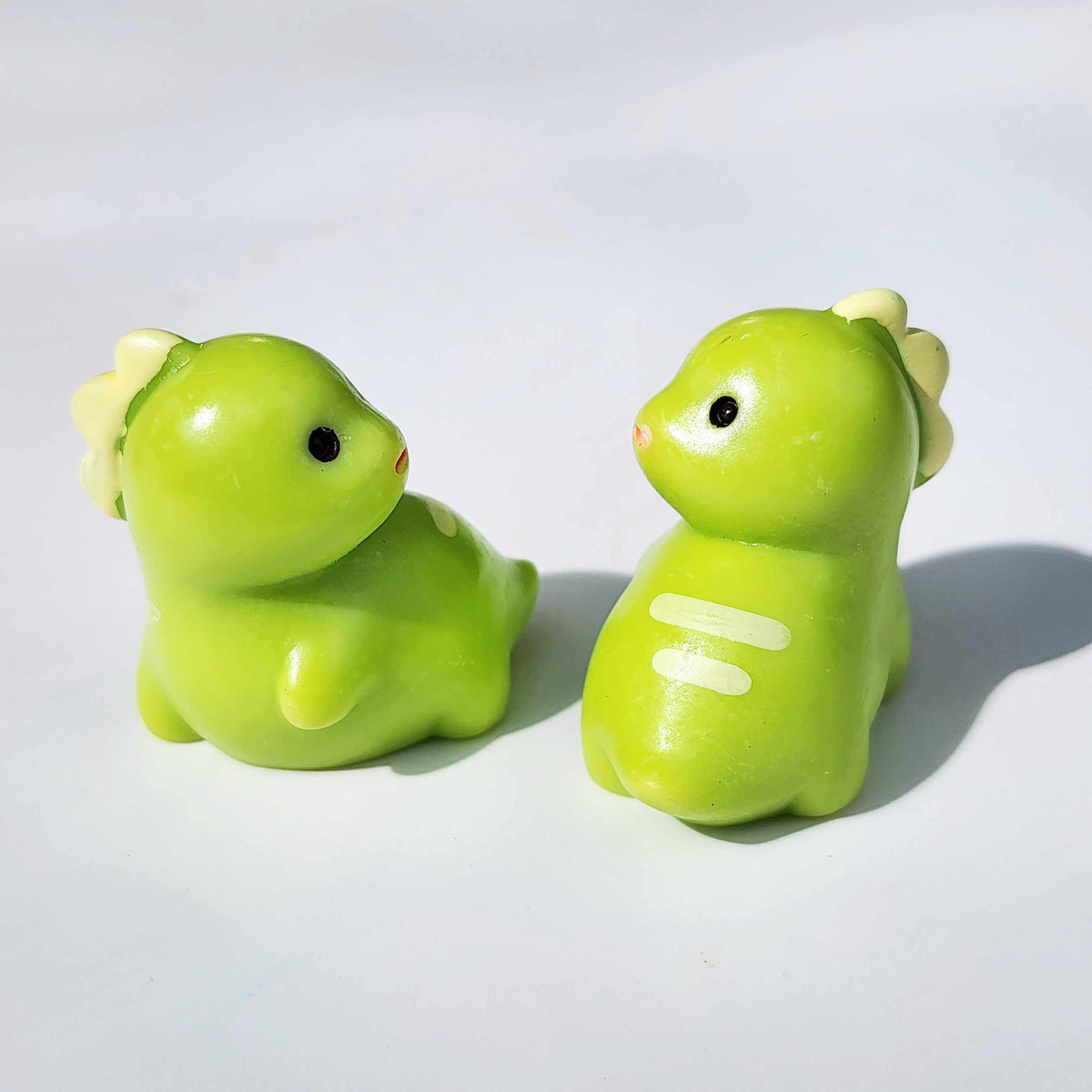 two fat looking green dinosaurs on a white background