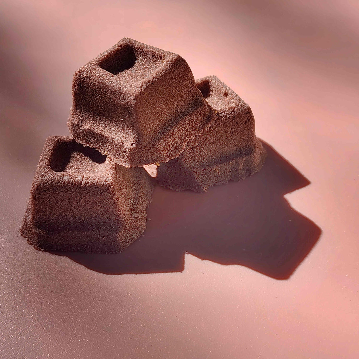 mini chocolate bath bombs shaped like cubes of chocolate on a plain brown background