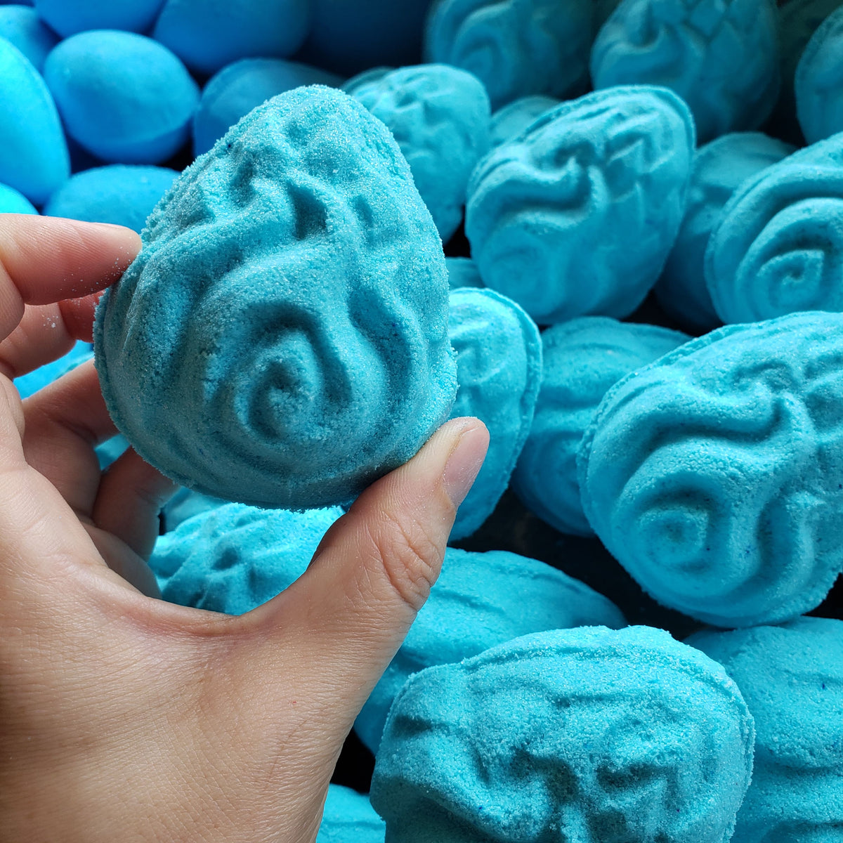bright teal egg shaped bath bombs with intricate carvings in the shape of flames