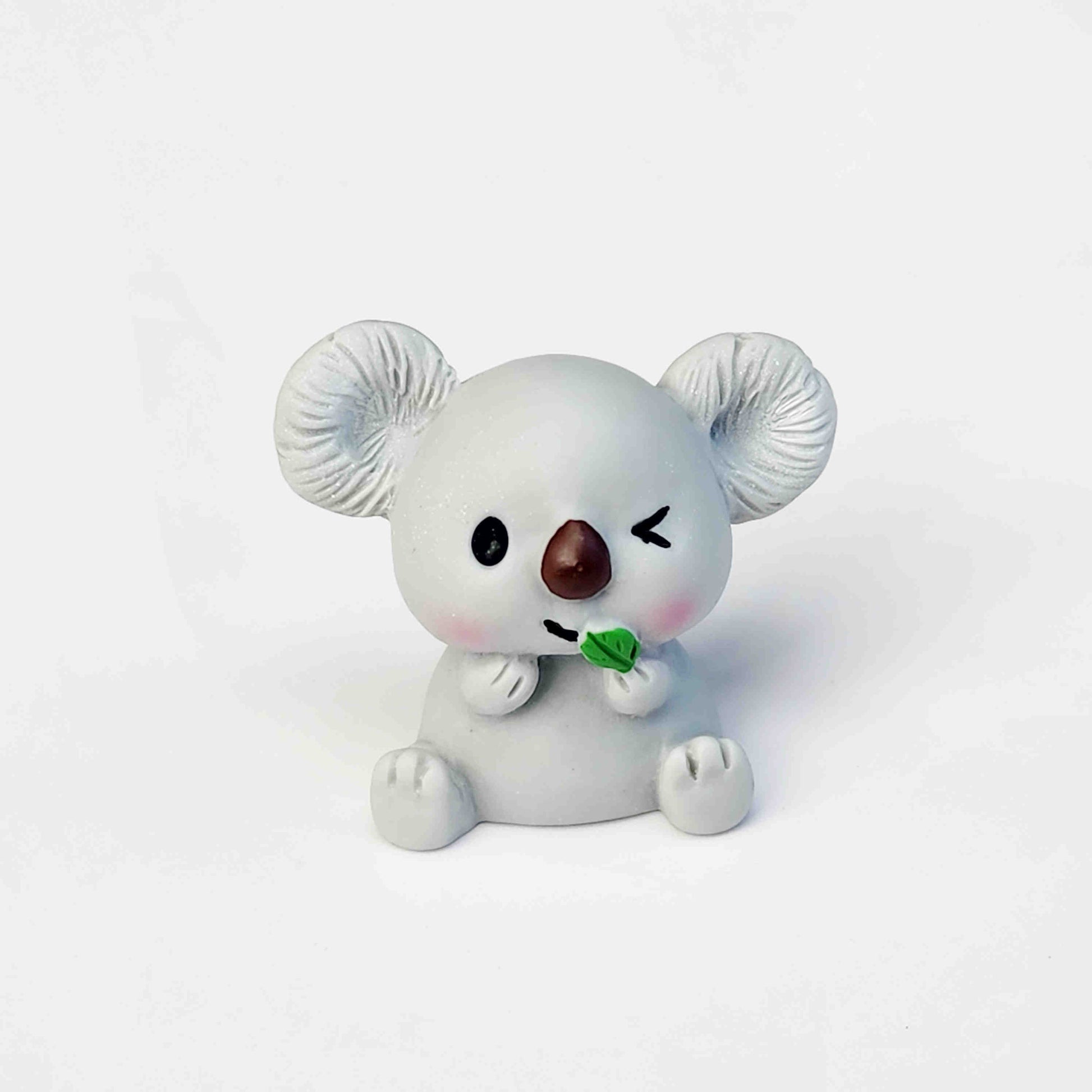 cute grey koala figurine sitting on a white background