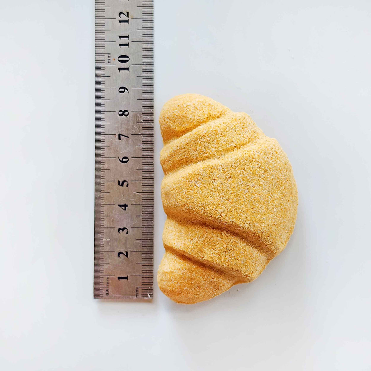 Croissant bath bomb measured beside a ruler