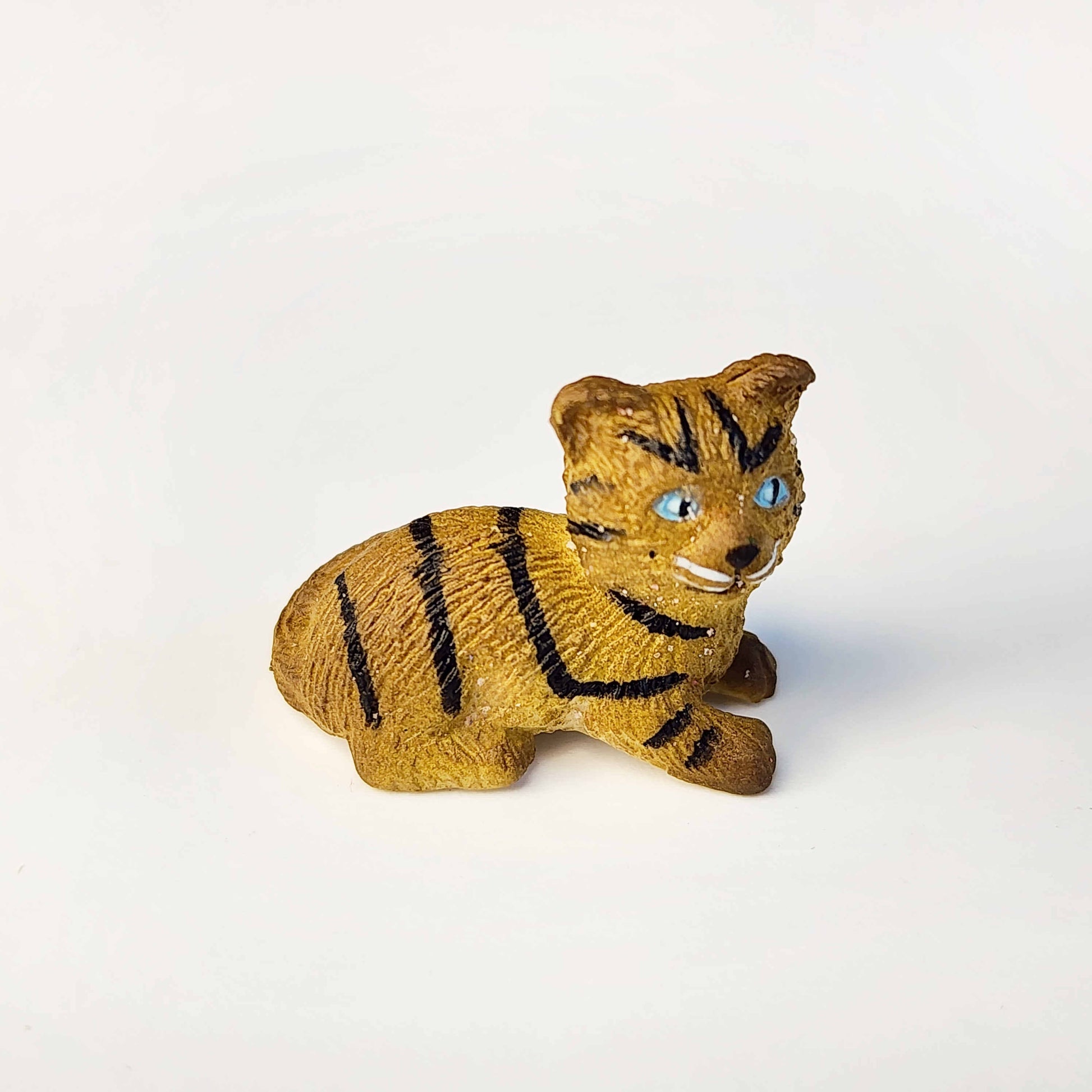 brown tabby pvc cat figurine laying down on a white background