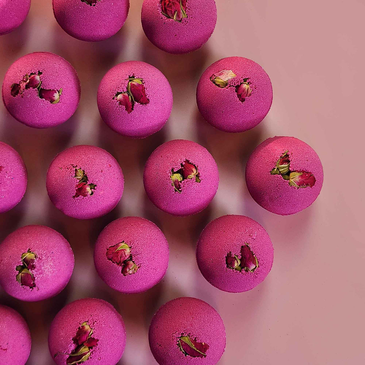 velvet red round aromatherapy bath bombs with dried rose buds on a dusty pink background