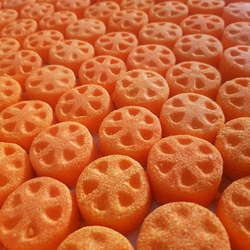 Orange slice shaped mini bath bomb layed out in an array across a plain neutral background