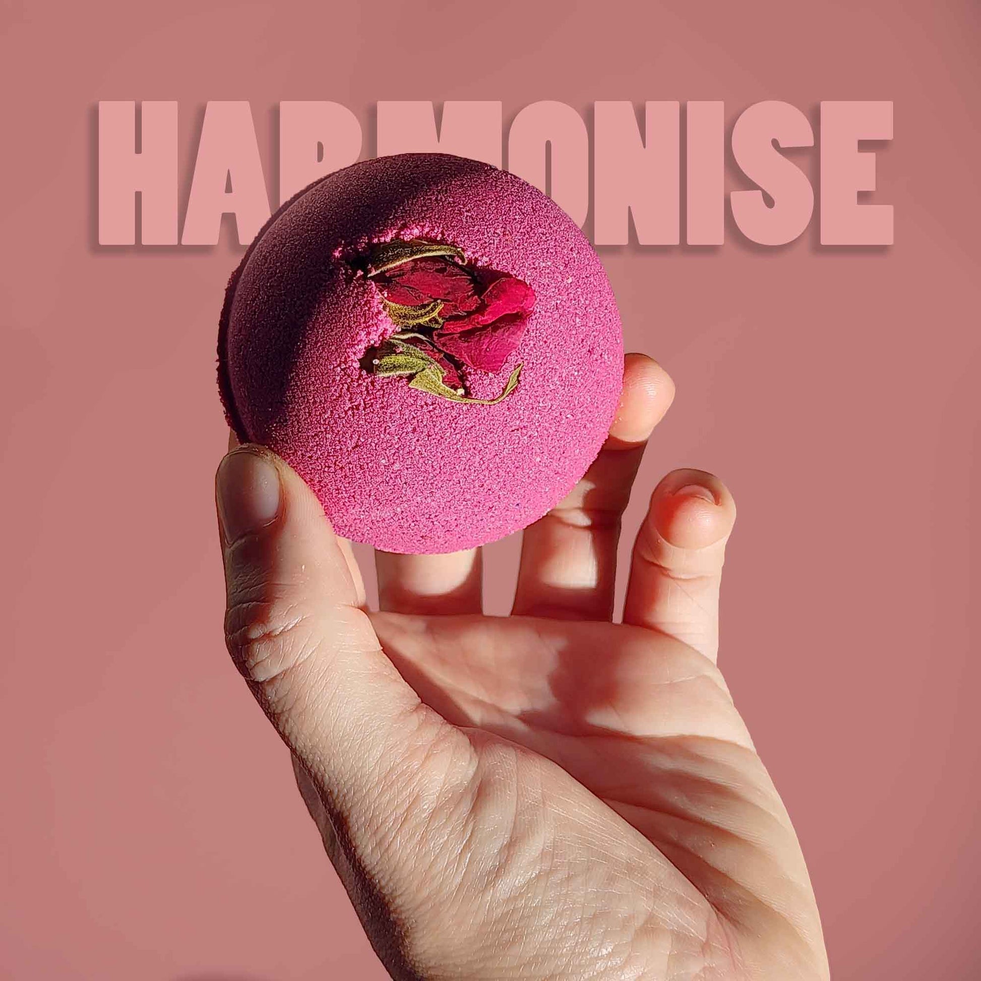Hand holding the pink Harmonise aromatherapy bath bomb