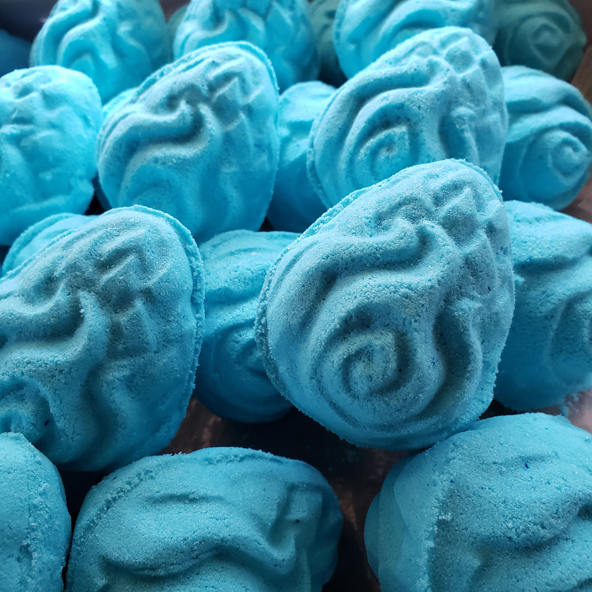 bright teal egg shaped bath bombs with intricate carvings in the shape of flames