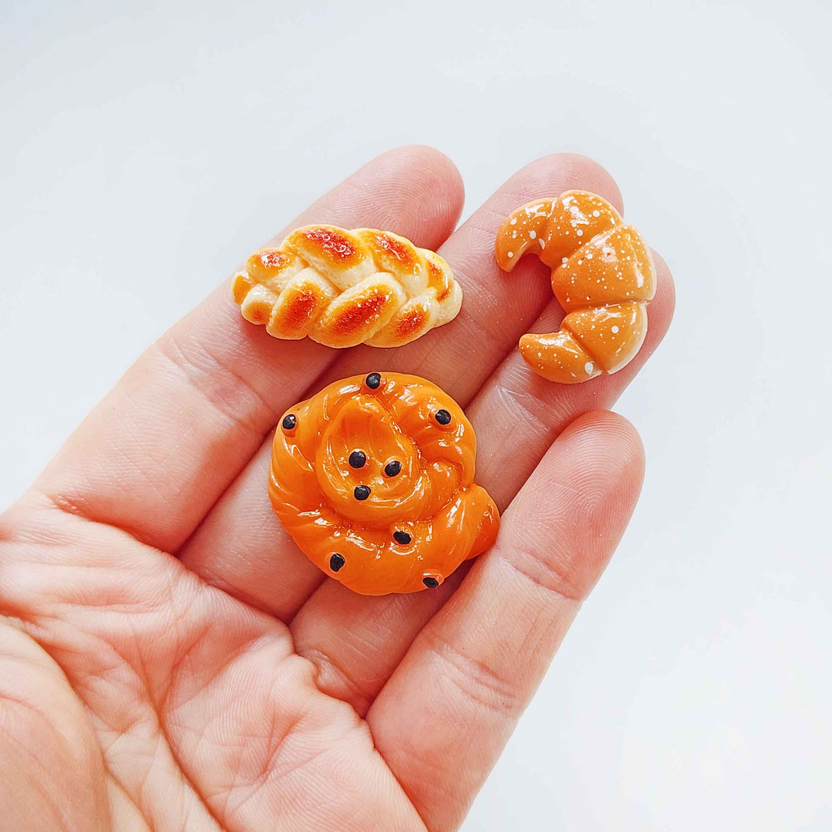 Hand holding three miniature bread surprise toys