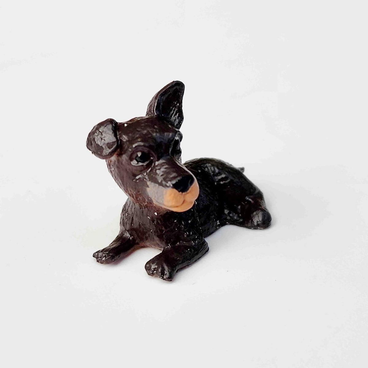 black and brown puppy dog figurine placed on a plain white background