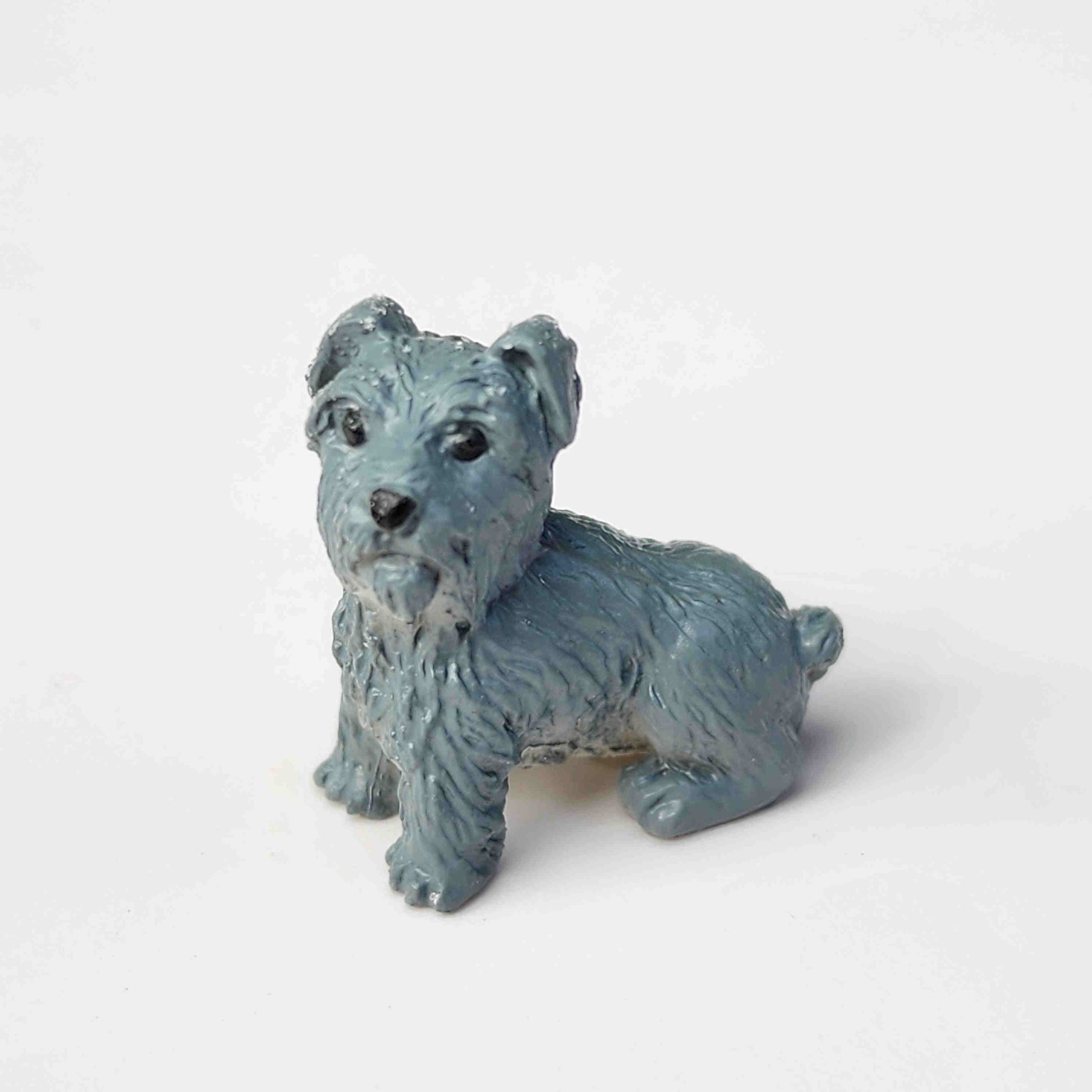 Grey puppy dog figurine placed on a plain white background