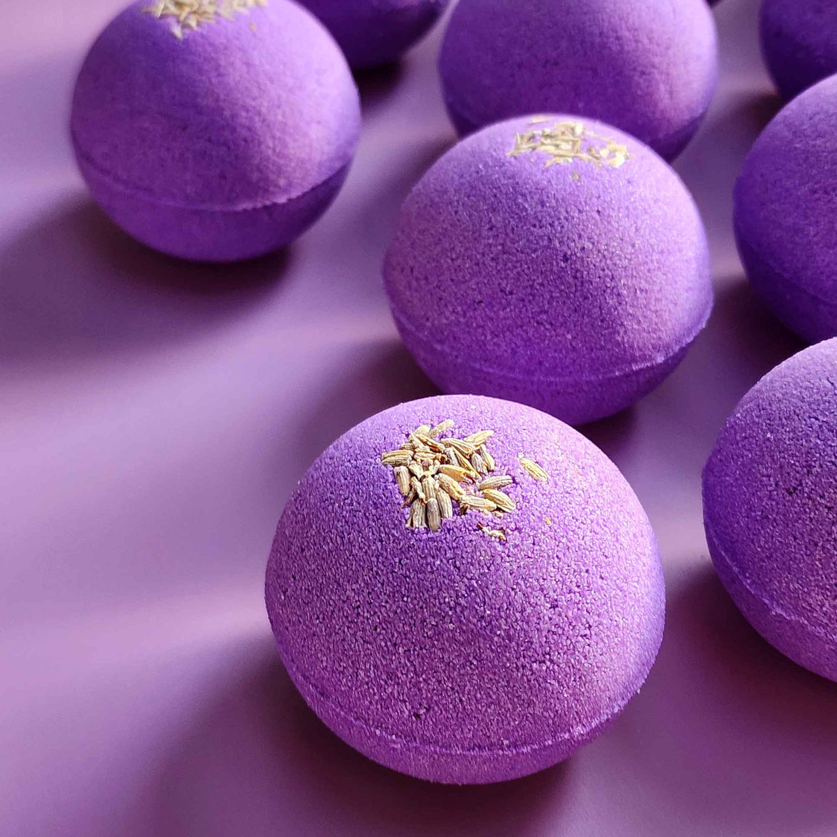 Close-up of two purple Relax bath bombs with lavender buds