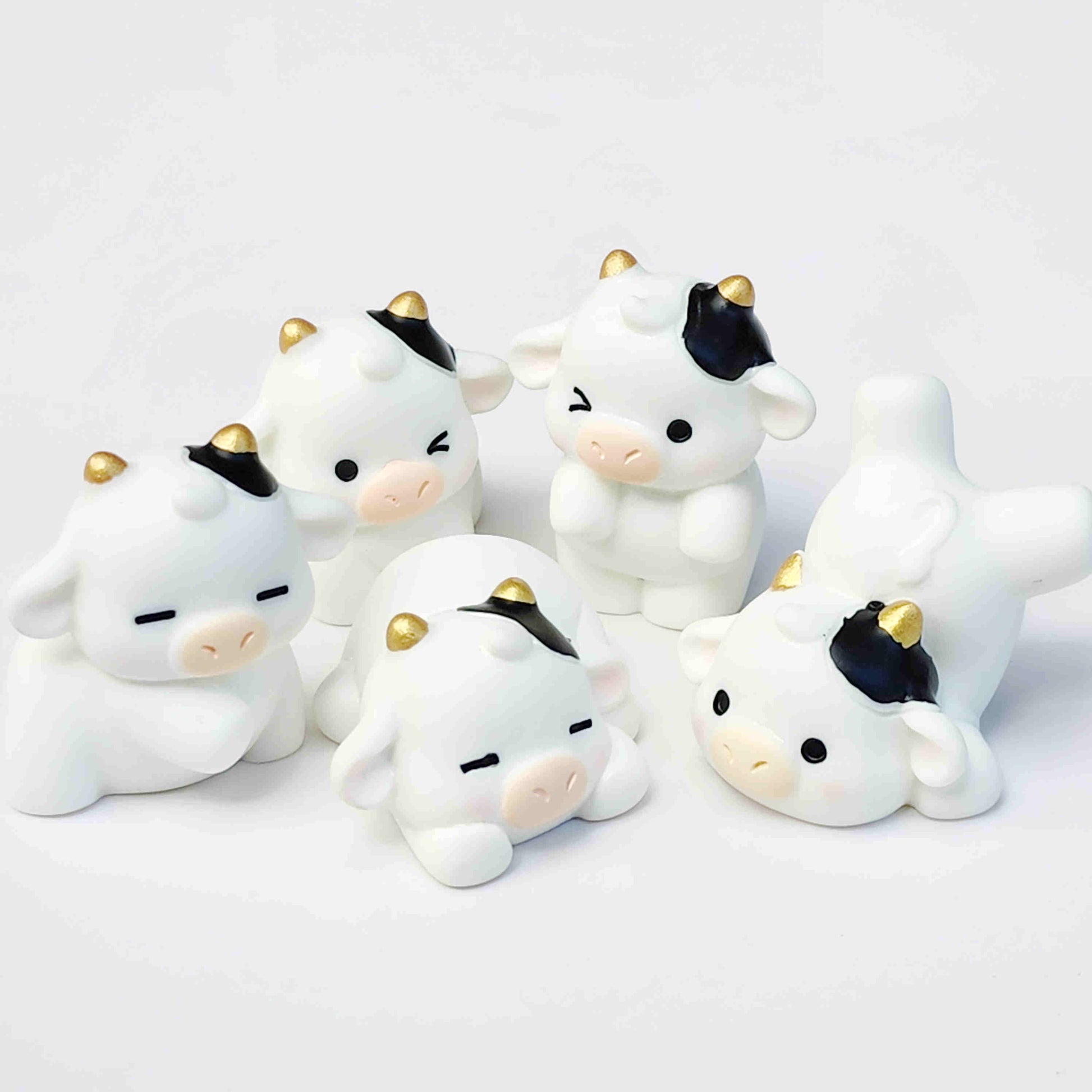 Group of cute cow figurines with gold horns on a white background