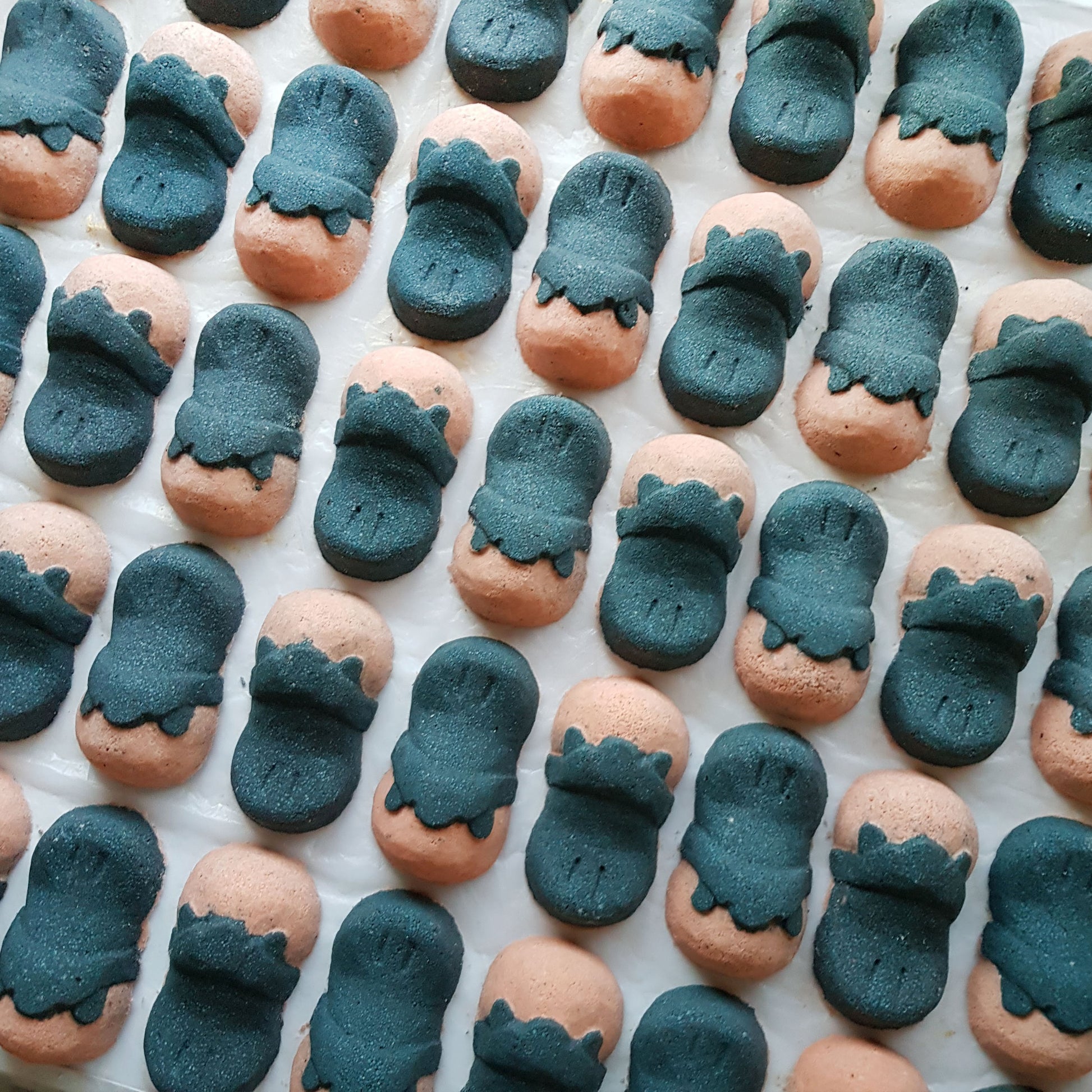 Rows of pink and charcoal Tea Tree platypus-shaped bath bombs