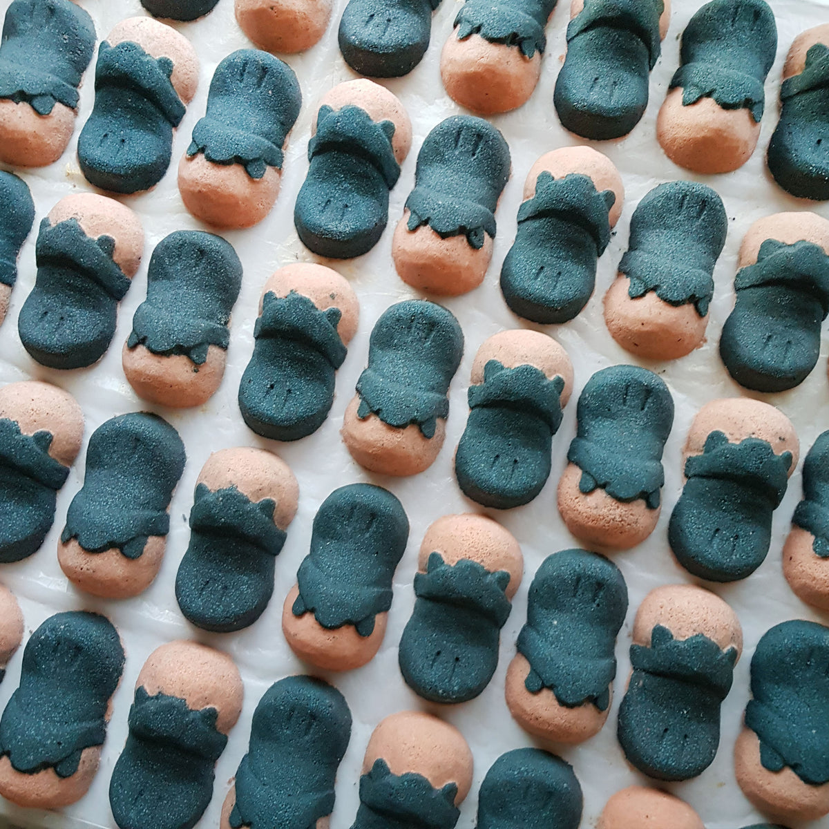 Rows of pink and charcoal Tea Tree platypus-shaped bath bombs