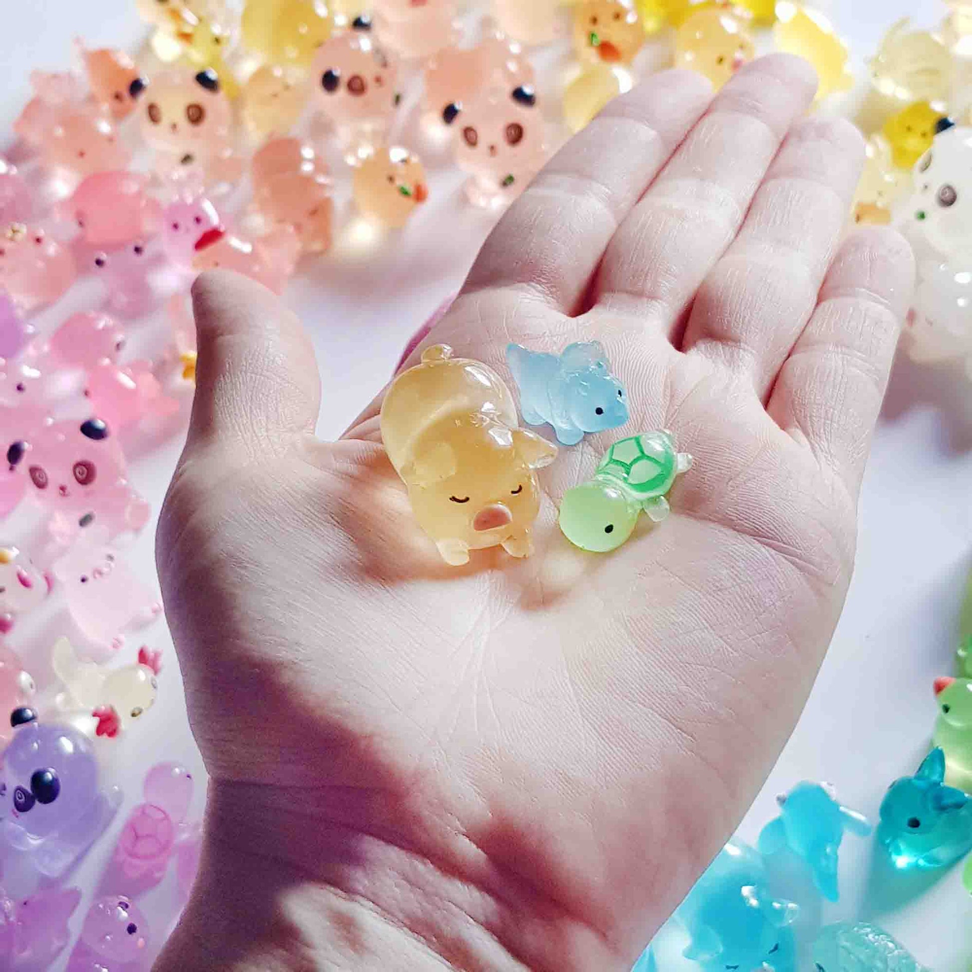 Hand holding three translucent fairy garden animal toys