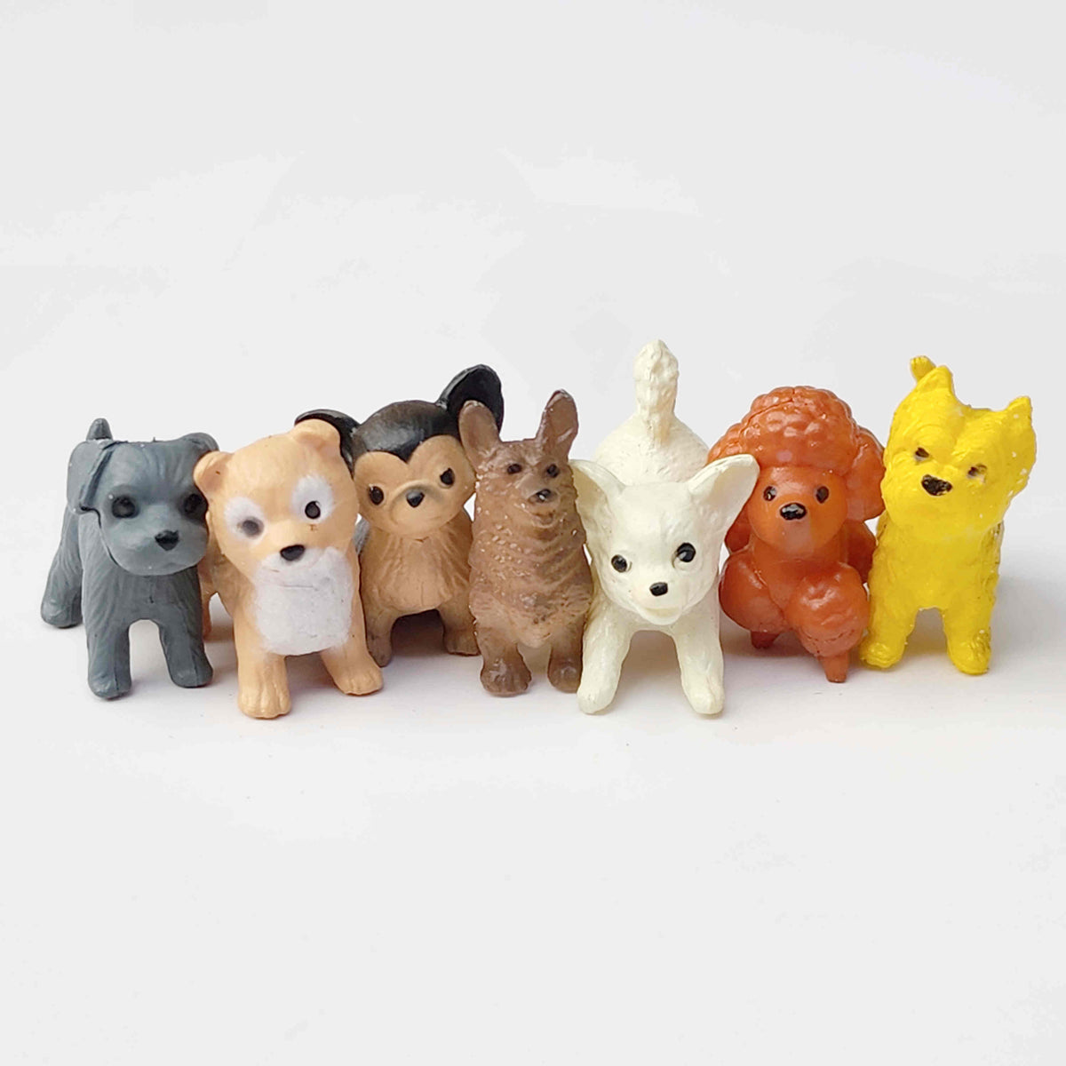 Group of PVC dog figurines standing in a row on a white background