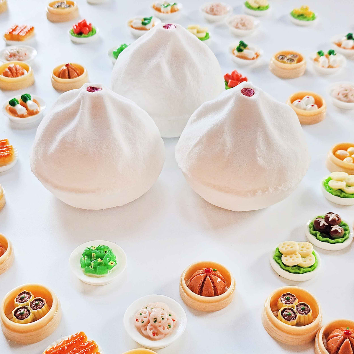 Three white bao bath bombs displayed among miniature dim sum toys
