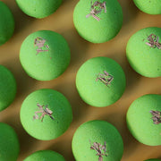 Multiple bright green Repair aromatherapy bath bombs topped with small pieces of dried lemongrass on a warm yellow background