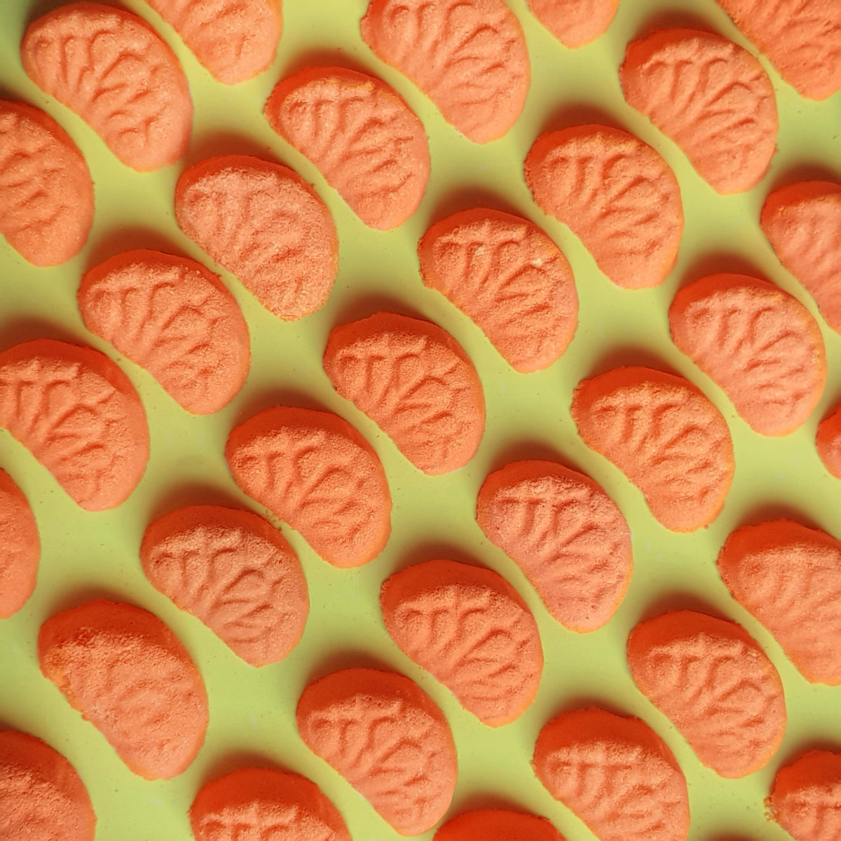 Miniature vibrant orange coloured mandarin bath bombs shaped as mini mandarin slices