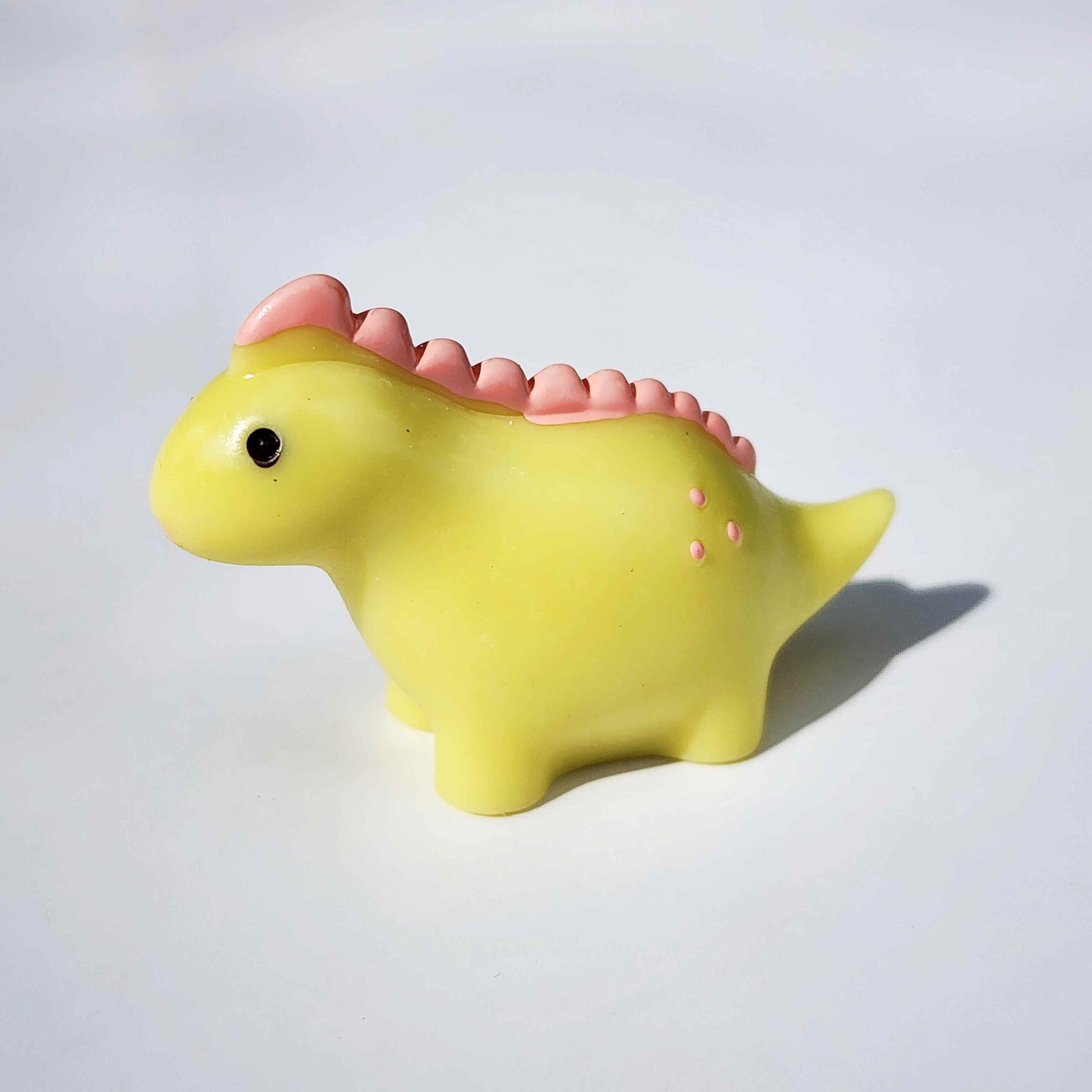 a round lime yellow coloured dinosaur on a white background