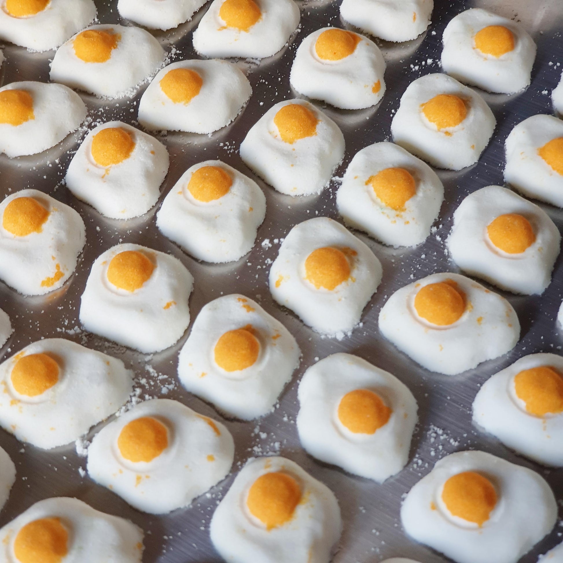 Mini sunny side up egg shaped bath bomb with a golden orange yolk