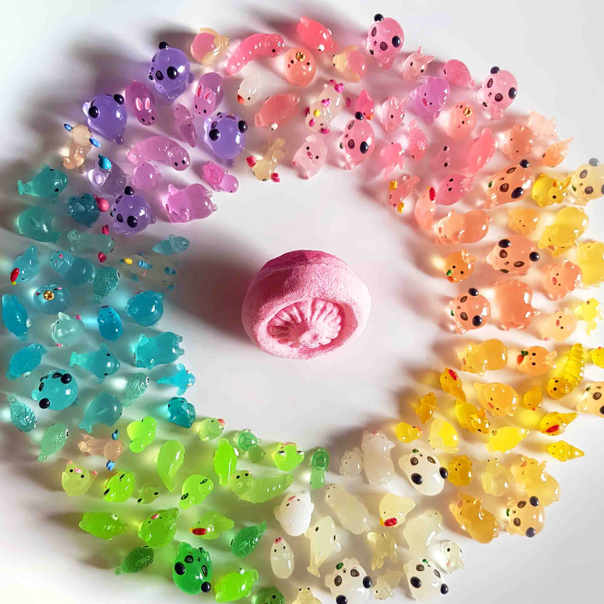 Pink mushroom bath bomb surrounded by colorful fairy garden toys