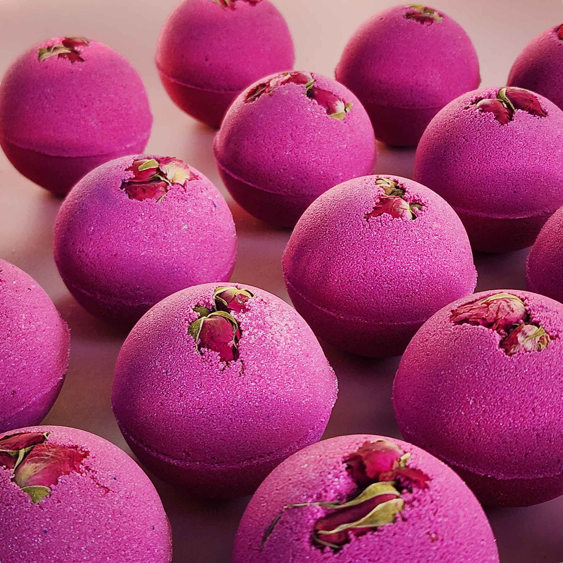 velvet red round aromatherapy bath bombs with dried rose buds on a dusty pink background