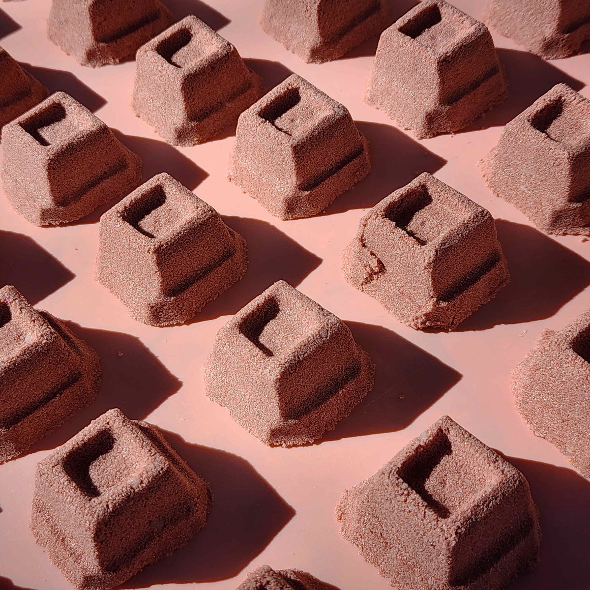 mini chocolate bath bombs shaped like cubes of chocolate on a plain brown background