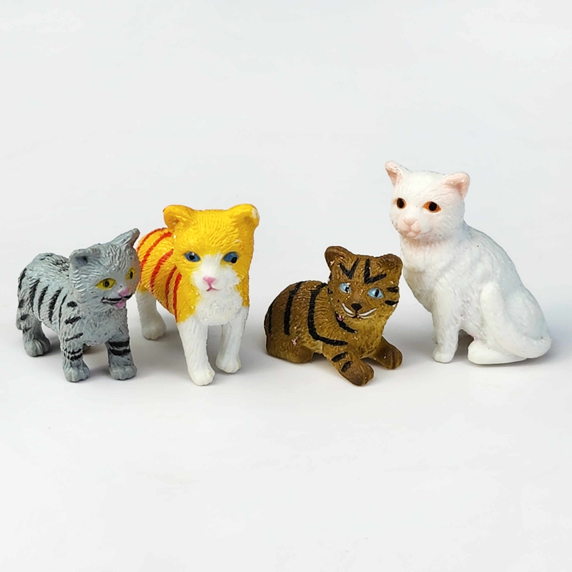 row of miniature cat figurines on a white background