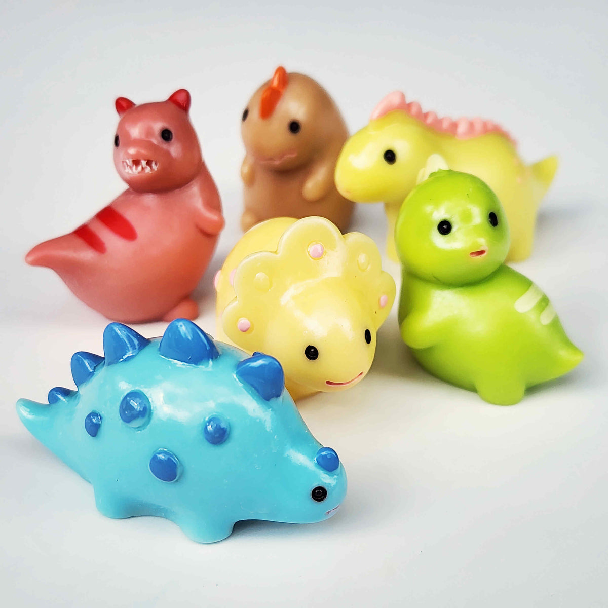 group of colourful round dinosaurs on a white background