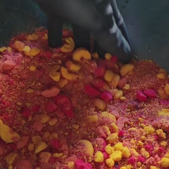 powdered bath bombs in a mixing bowl with fruit loop shaped bath bombs in the background